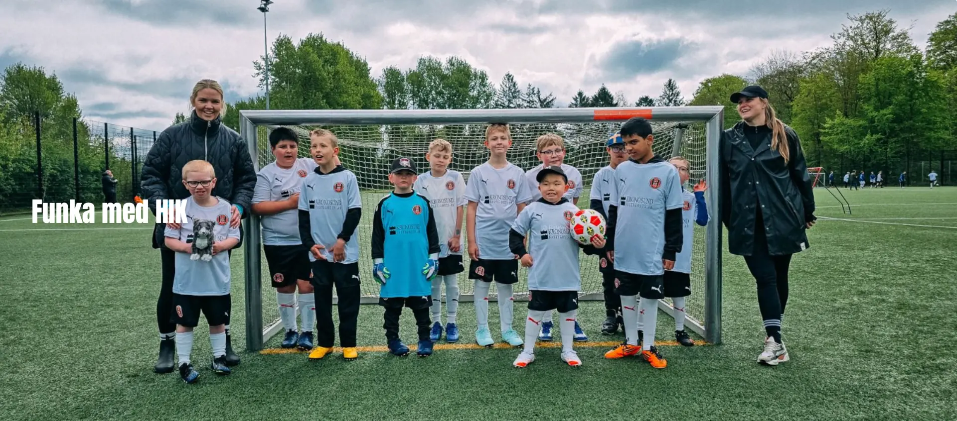 Hittarps IK:s lag i tröjor med Kronosunds logotyp framför fotbollsmålet